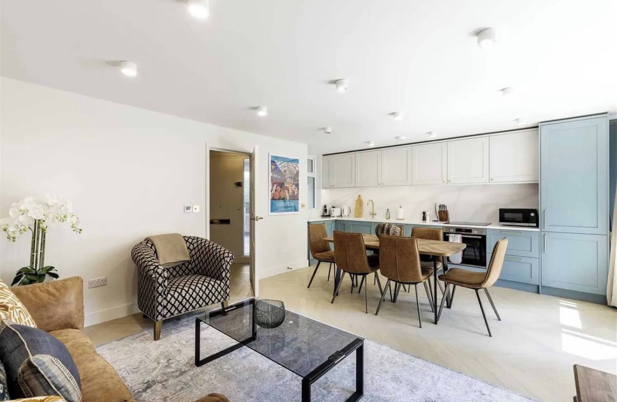 Een moderne woonkamer met een bank, een glazen salontafel, en een eethoek met stoelen en een tafel.