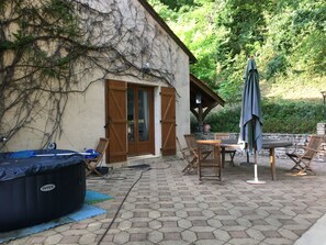 Terassialue, jossa on poreallas, puiset huonekalut ja kivimuuri.