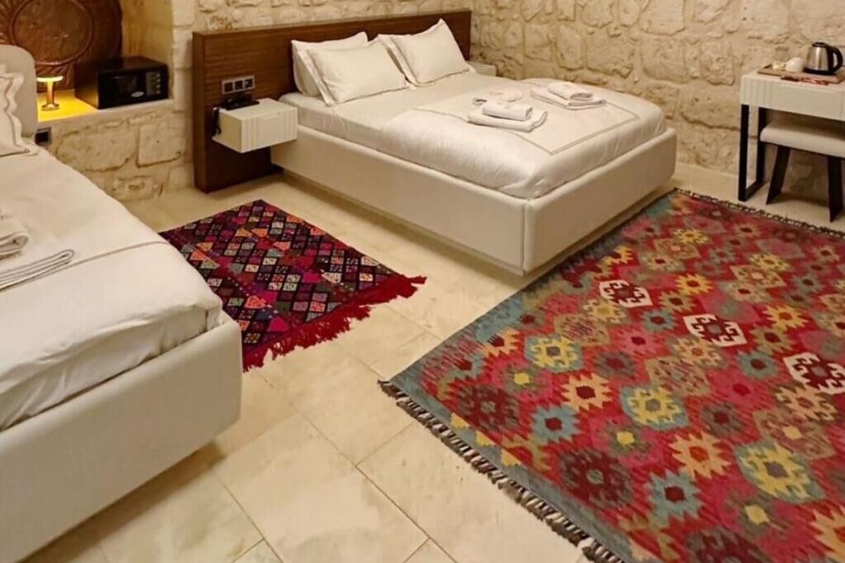Um quarto aconchegante com paredes de pedra, uma cama, uma mesa pequena e um tapete decorativo.