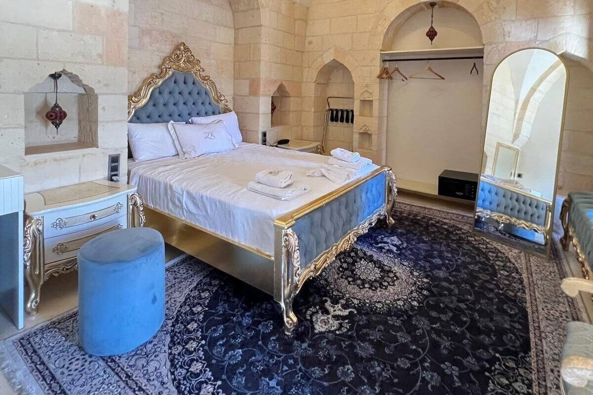 Quarto com uma cama grande, um candelabro e paredes de pedra.