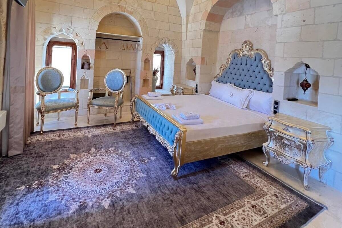 Quarto com uma cama grande, um lustre, paredes de tijolos em arco e um tapete estampado.
