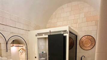 Una habitación de hotel con cama, baño, una mesita y una lámpara de techo original.