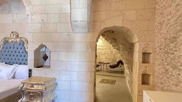 A room with a bed, a nightstand, a dresser, and an arched doorway leading to another room.