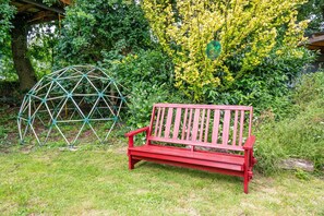A red bench in a garden with a geodesic dome structure and lush greenery. - Gina's Holiday Home with Garden, Treehouse Terrace and Sauna (Eggstedt)