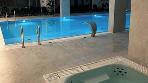 En swimmingpool med jacuzzi, liggestole og moderne indretning.