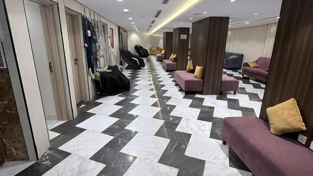 Un hall de hotel con suelo a cuadros, zonas de estar y un pasillo que conduce a las habitaciones.
