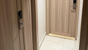 Un pasillo con puertas de madera, un interruptor de luz y piso de baldosas.