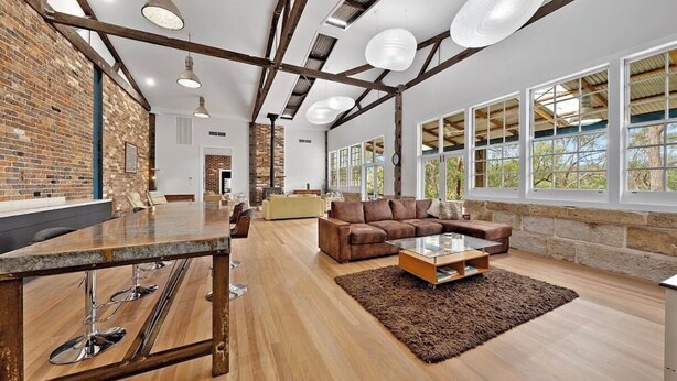 Amplia sala de estar con piso de madera, zona de bar con mostrador y un gran ventanal con vistas al exterior.