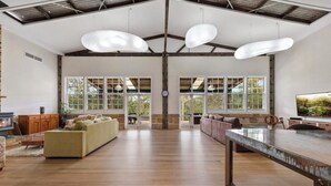 Un salón amplio con techo alto, ventanas grandes y chimenea.