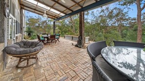 Un patio cubierto con muebles de mimbre, una mesa y una estatua de Buda.