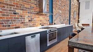 Una cocina moderna con pared de ladrillo, electrodomésticos de acero inoxidable y encimera de mármol.