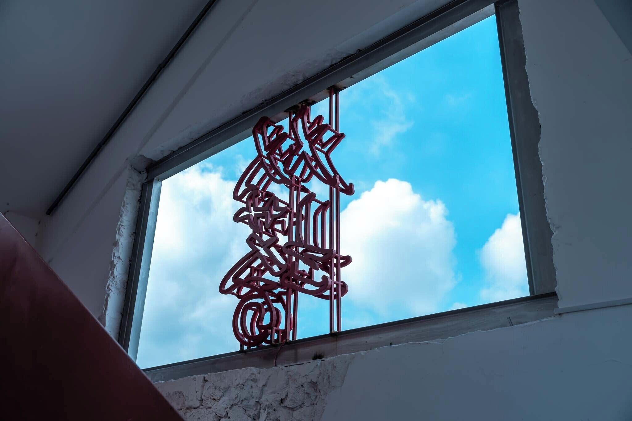 Janela com um detalhe metálico decorativo e céu azul límpido.