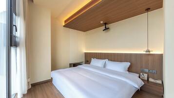 Ein modernes Hotelzimmer mit einem großen Bett, einem Holz-Kopfteil und einer Deckenleuchte.