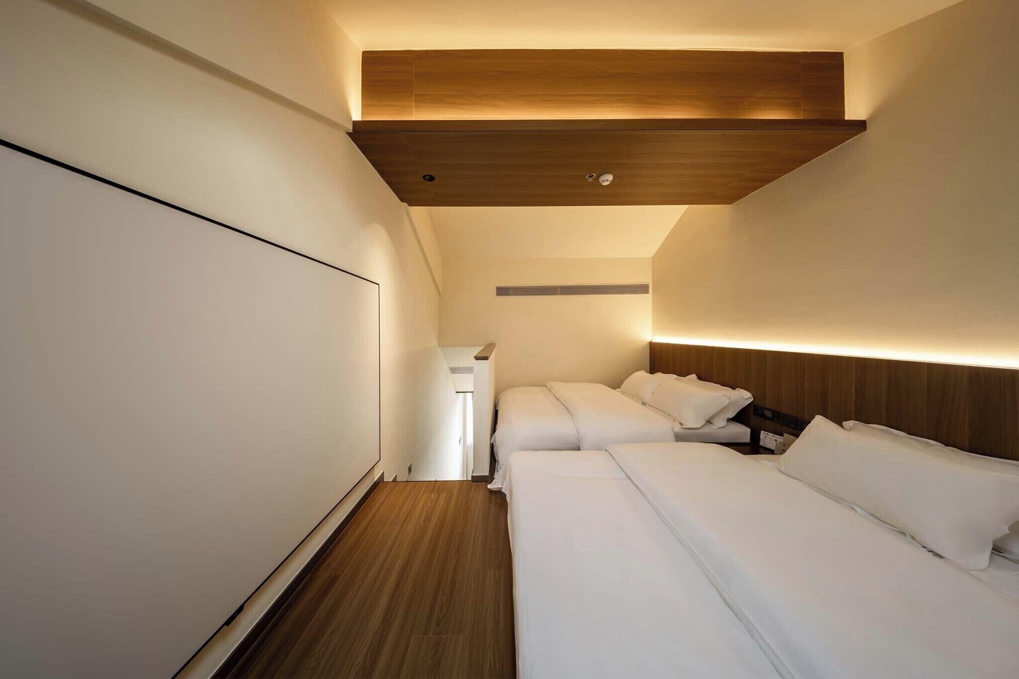 Habitación de hotel con dos camas, techo de madera y armario blanco.