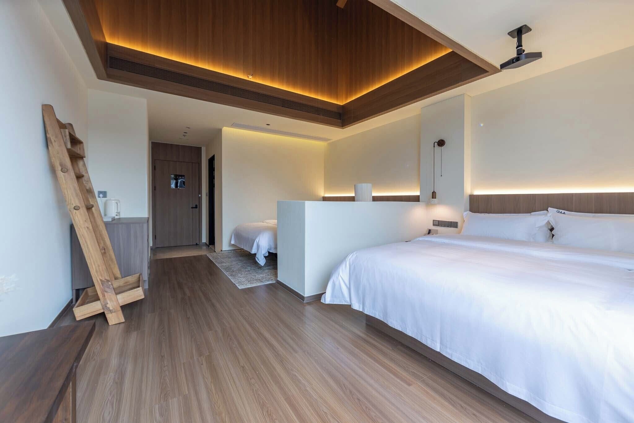 A modern hotel room with a wooden ceiling, a large bed, a desk, and a small bathroom.
