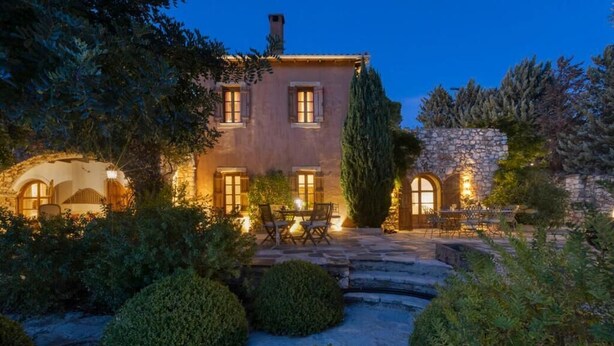 A stone building with a patio and outdoor seating, surrounded by greenery.