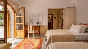A room with two beds, a desk, a chair, a large window, and a wardrobe.
