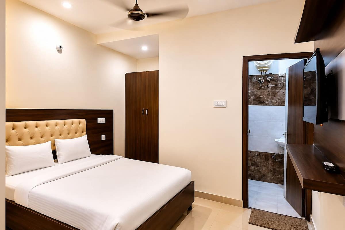 A hotel room with a bed, a wardrobe, a television, and a bathroom visible through an open door.