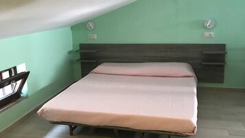 A bedroom with a bed, a window, and a wall-mounted light fixture.