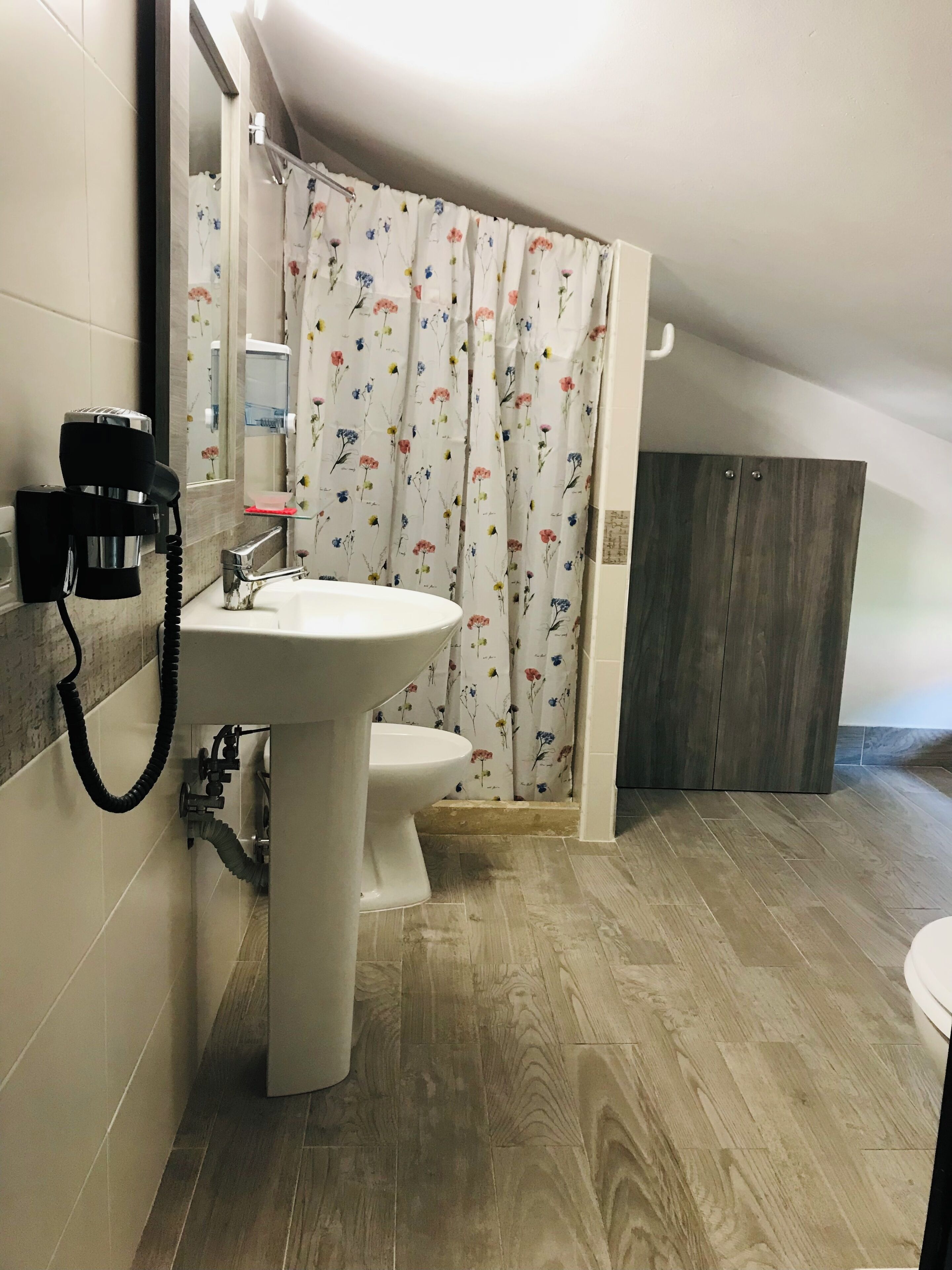 Une salle de bain équipée d’un lavabo, de toilettes, d’un rideau de douche et d’un sèche-cheveux.
