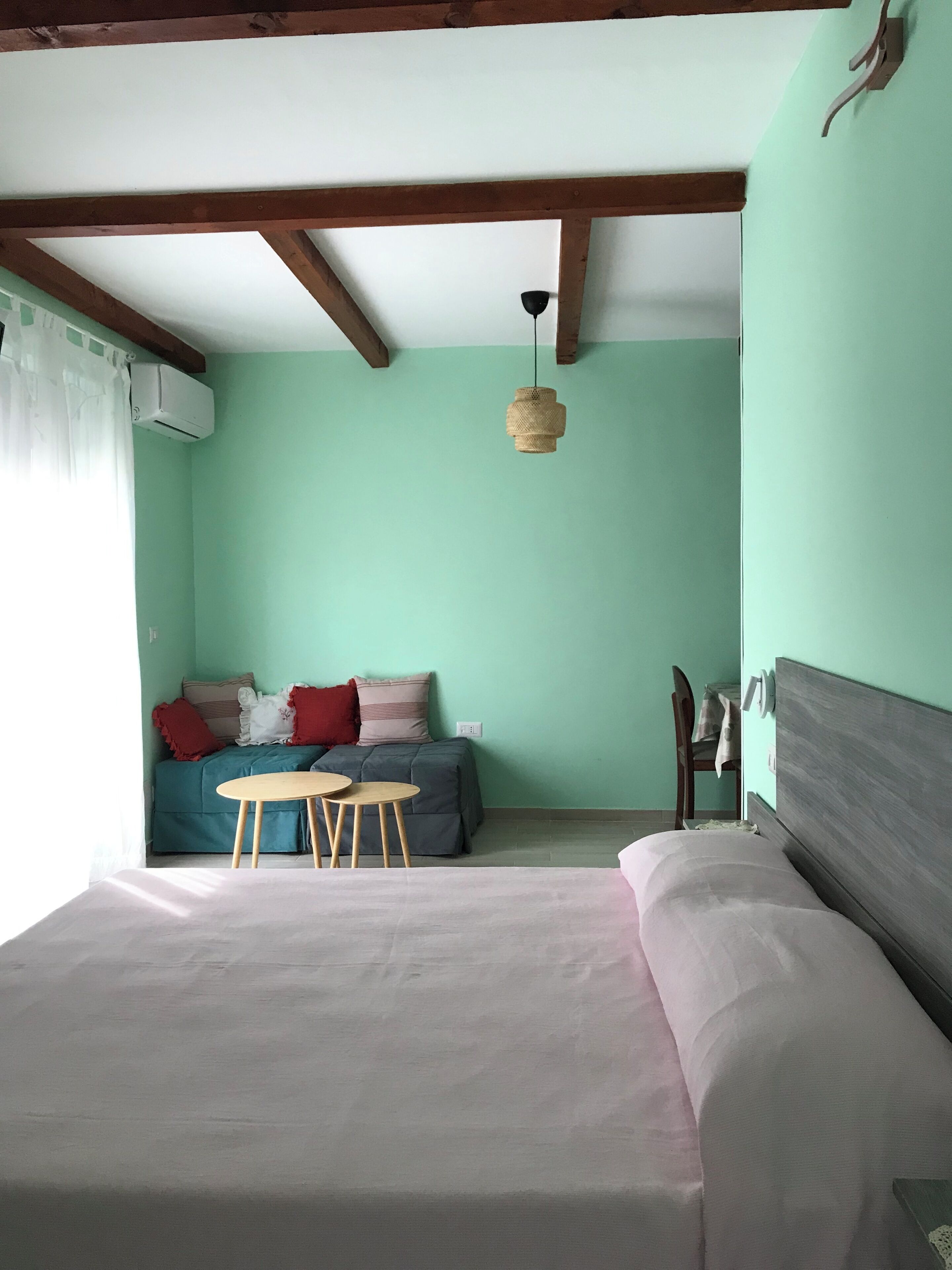 Ein Zimmer mit einem Bett, einem kleinen Tisch, einer Couch und einer Pendelleuchte.