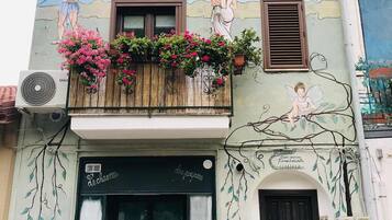 Ein Gebäude mit Wandmalerei, einem Balkon mit Blumen und einer schwarzen Tür.