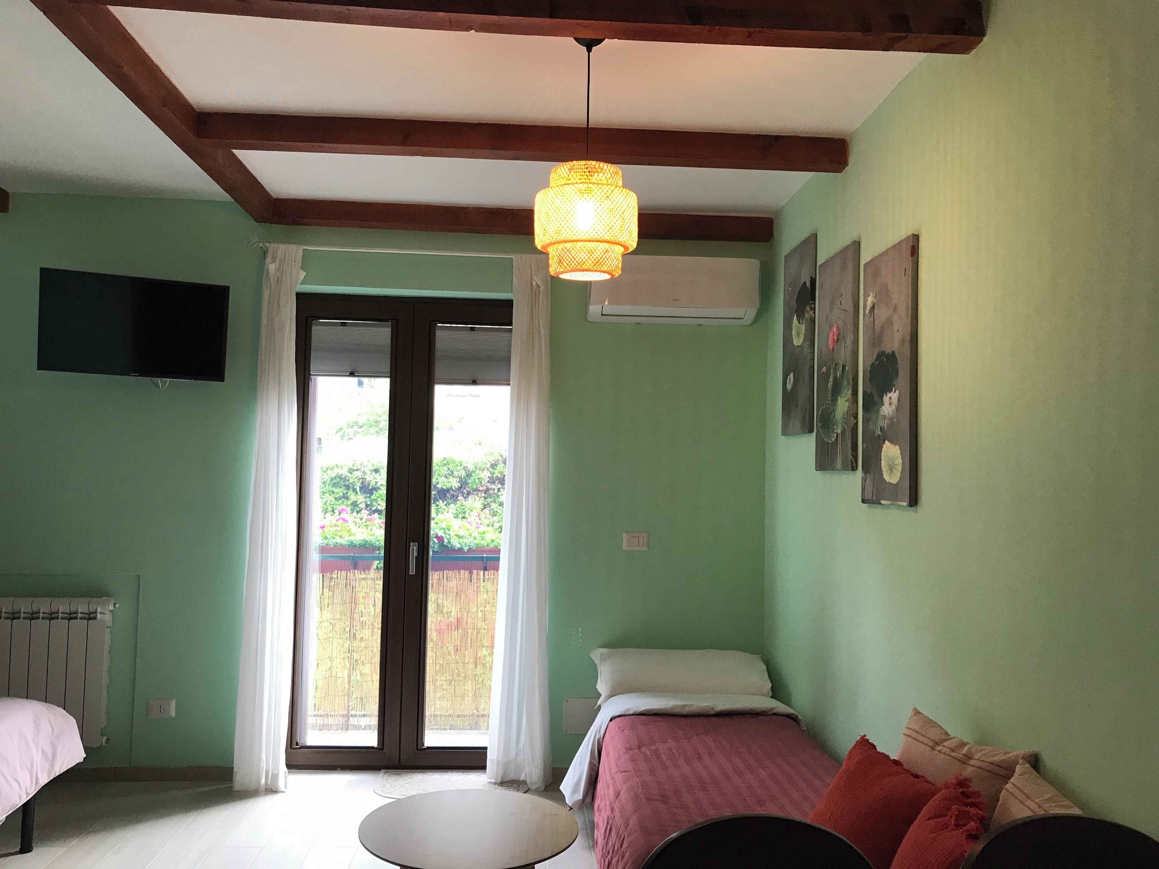 Una habitación con una cama, una mesa redonda, un televisor y un ventanal con cortinas.