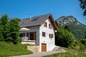 Una casa moderna con techo inclinado, base de piedra y puerta de madera.
