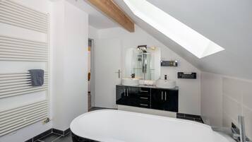 A modern bathroom with a freestanding bathtub, a large mirror, and a black vanity.