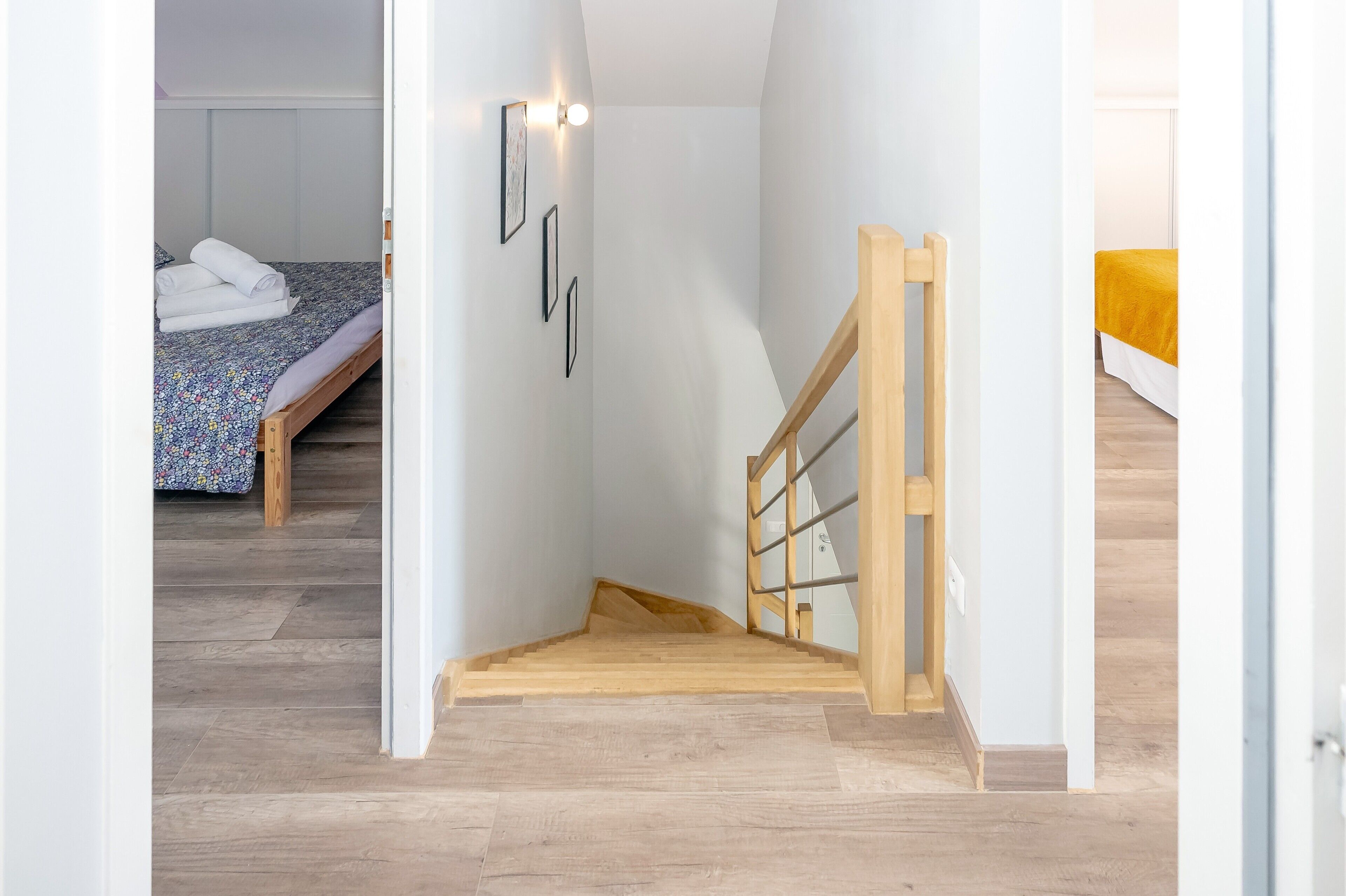 Una stretta scala conduce a una camera da letto con un letto e un punto luce a parete.