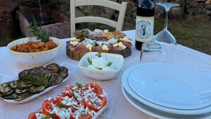 Mesa al aire libre con comida, una botella de vino y una copa.