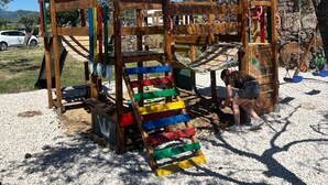 Un parque infantil con una estructura de madera para escalar, un tobogán y una mesa.