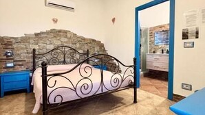 Un dormitorio con cama, pared de piedra, puerta azul y armario azul.