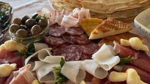 Una tabla de embutidos con diferentes carnes, quesos y aceitunas.