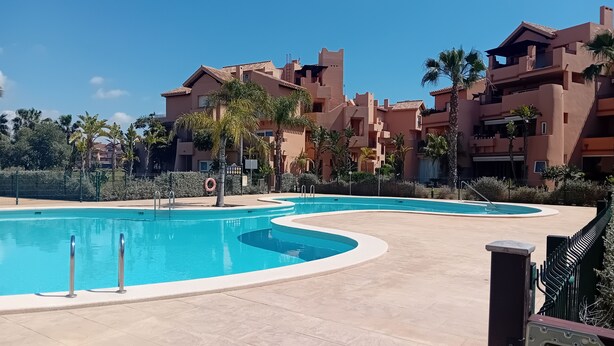 Une piscine au design incurvé, entourée d’une terrasse carrelée.