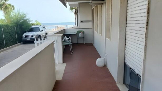 A balcony with a red-tiled floor, a white fence, and a parked car. - ON THE SEA Casalbordino Lido Costa dei Trabocchi (Termini)