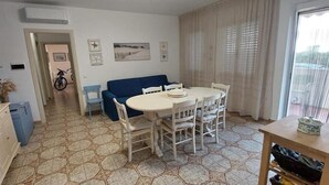 A dining area with a round table and chairs, a blue sofa, and a kitchen area with cabinets and a stove. - ON THE SEA Casalbordino Lido Costa dei Trabocchi (Termini)
