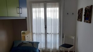 A bedroom with a bed, a chair, a wardrobe, a ceiling fan, and a door leading to a balcony. - ON THE SEA Casalbordino Lido Costa dei Trabocchi (Termini)