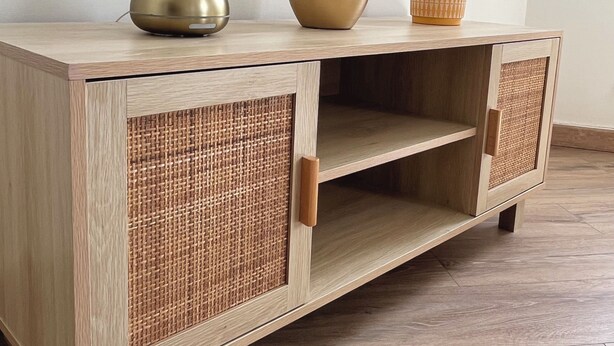 Un mueble de madera con paneles trenzados y un cajón, que exhibe un jarrón y dos cuencos encima.