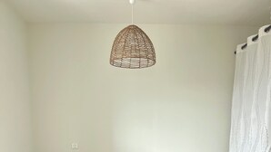 Un dormitorio con cama, almohadas, mesita de noche, lámpara y una lámpara colgante.