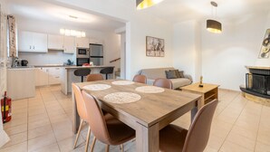 Una cocina moderna con gabinetes blancos, una mesa de comedor con individuales y una chimenea.