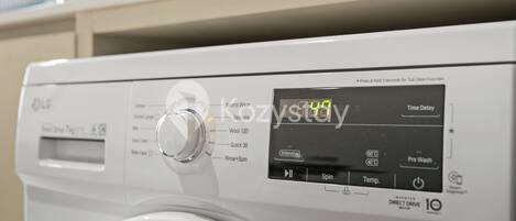 A front-loading washing machine with a digital display, control knobs, and various washing settings.