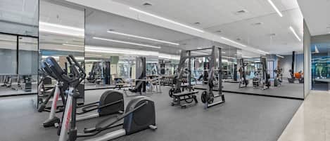 A gym with cardio equipment, weight machines, and mirrors on the walls.