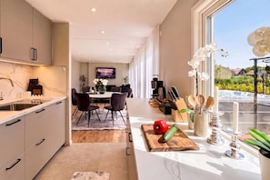 A modern kitchen with a dining area, a TV, and a view of the outdoors. - Seavista Trelleborg Sea View & Jacuzzi (Trelleborg)