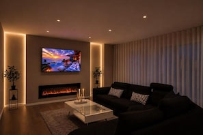 A modern living room with a flat-screen TV, a fireplace, a black sofa, and a glass coffee table. - Seavista Trelleborg Sea View & Jacuzzi (Trelleborg)