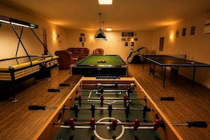 Una habitación con mesa de fútbol, mesa de billar y mesa de ping pong.