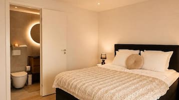 A bedroom with a bed, a bedside table with a lamp, and a circular wall light.