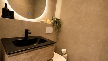 A bathroom with a black sink, a toilet, and a mirror.