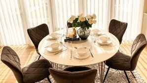 A round dining table set for six with a vase of white flowers, a sign reading 'Dine Couture,' and a book titled 'Dine Couture.' - Seavista Trelleborg Sea View & Jacuzzi (Trelleborg)