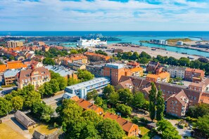 An aerial view of a coastal town with buildings, a harbor, and a large ship docked.